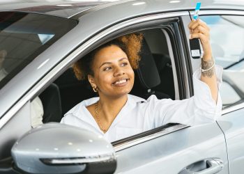 happy woman in new car holding car keys, used for an article on used vehicles