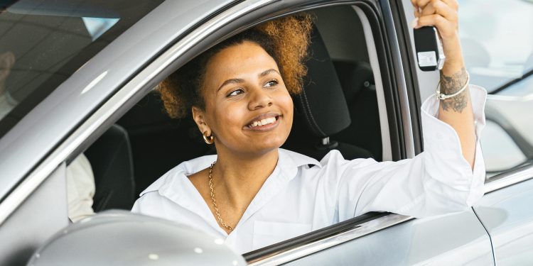 happy woman in new car holding car keys, used for an article on used vehicles
